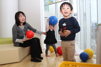 写真：ボールで遊ぶ母親と男の子と女の子